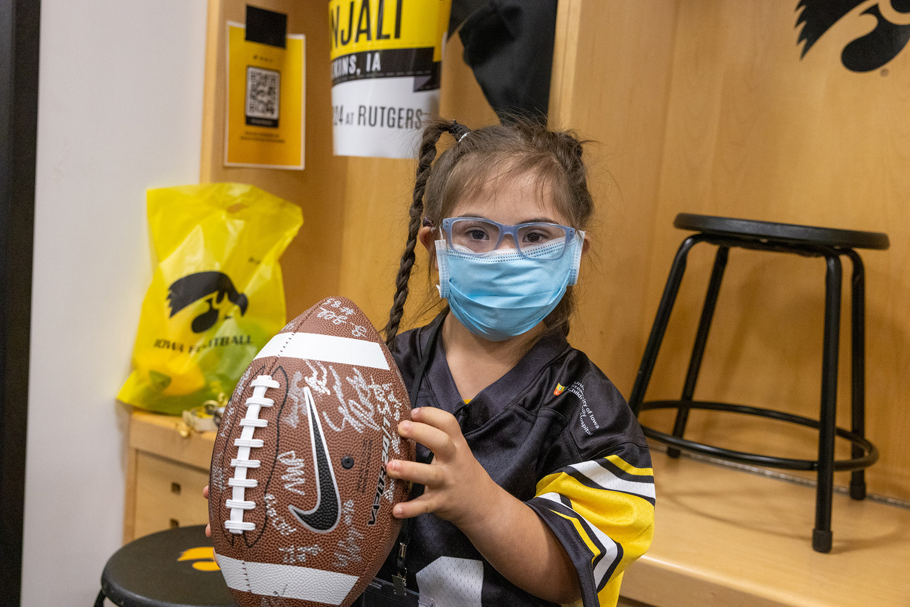 A girl holding a football with different signatures on it