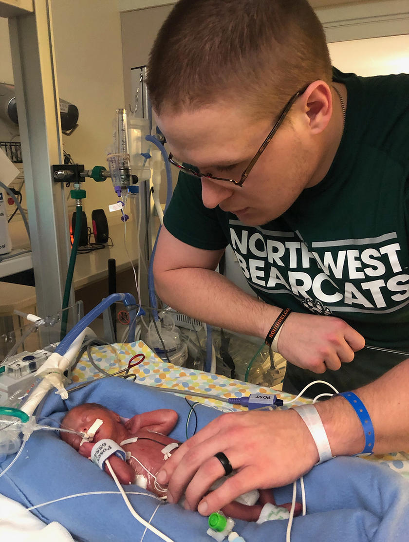 a man with a newborn infant born at 27 weeks
