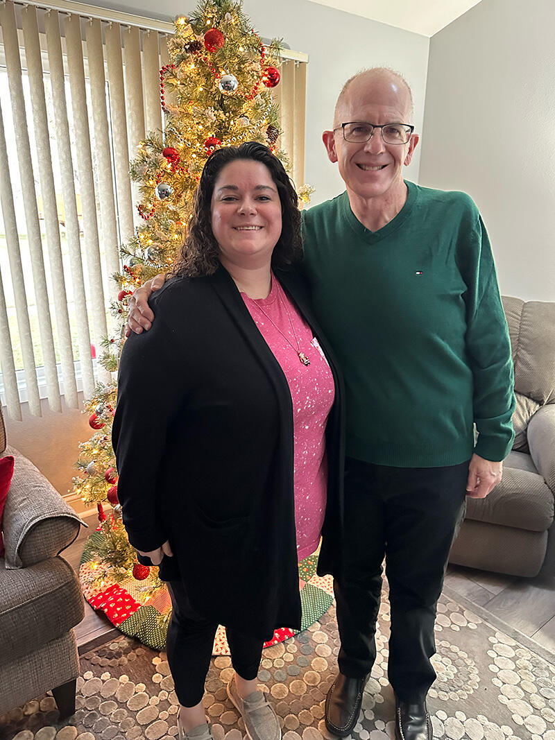 Two people standing together in front of a Christmas tree