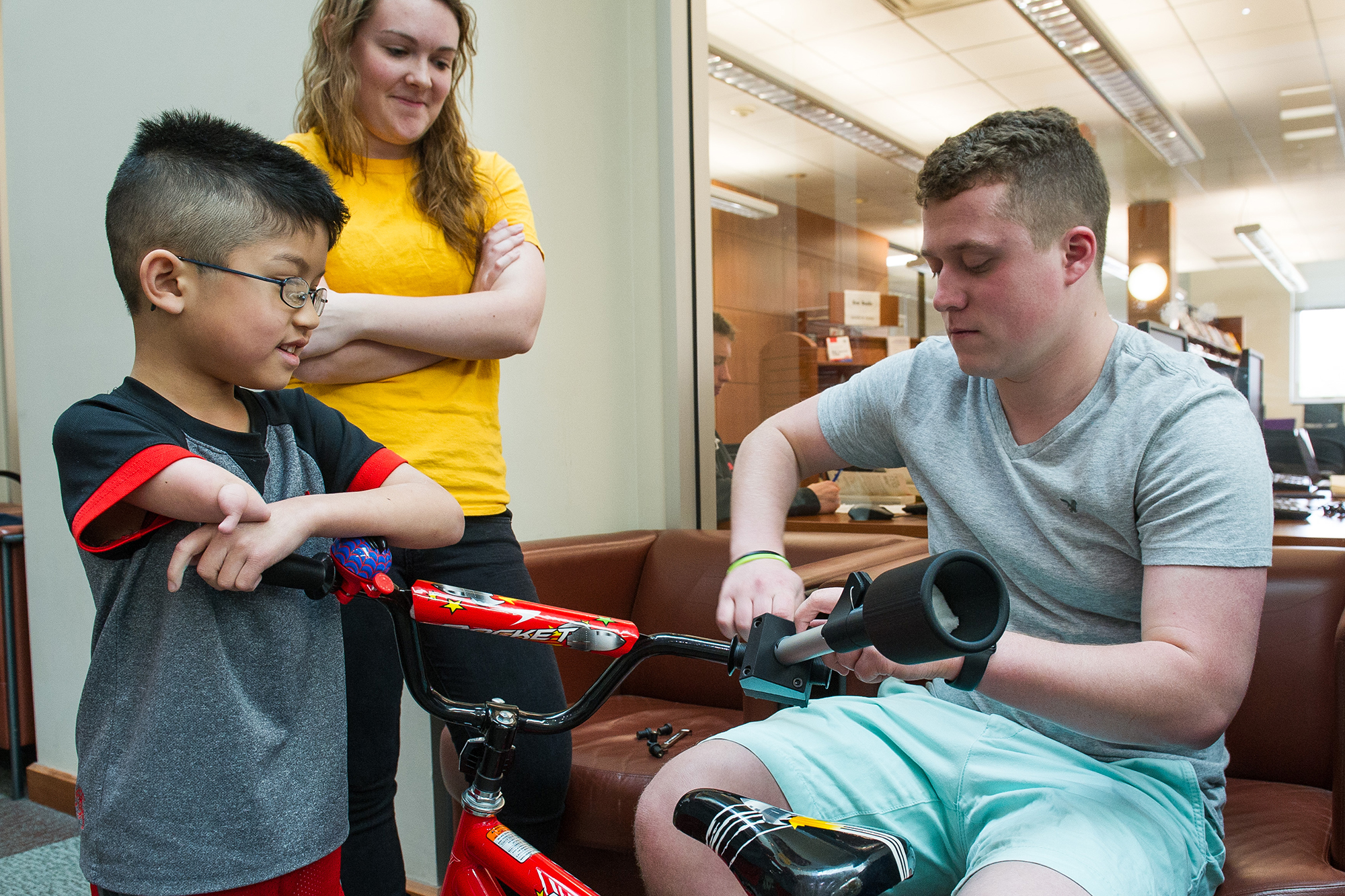 A boy leaning on a bike as it is adjusted
