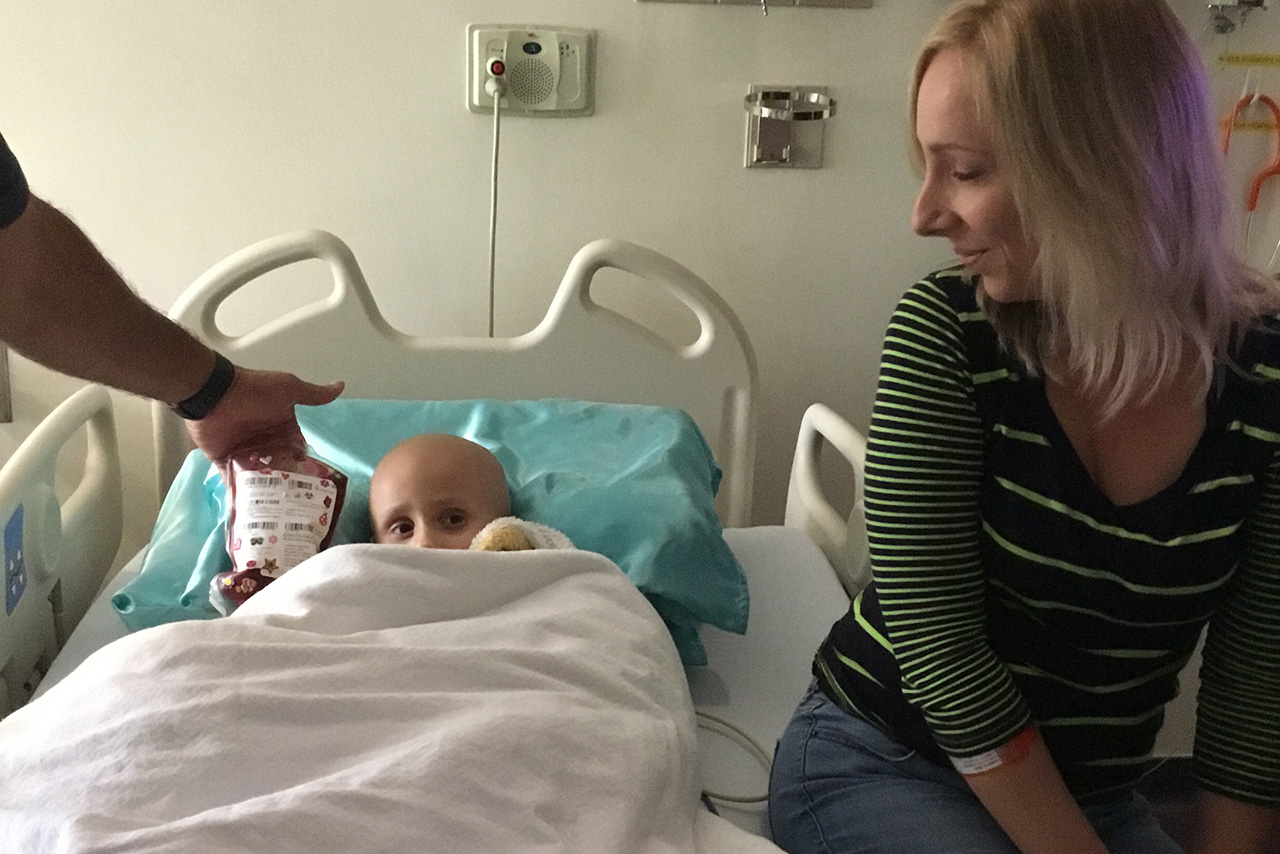 a woman sits next to her child on a hospital bed