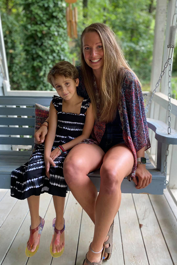 a girl and a young woman sitting together on a porch swing
