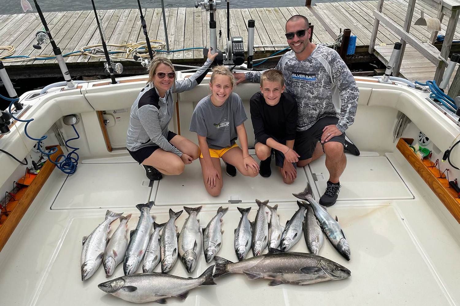 a family of four on a docked boat, displaying the day's catch of fish