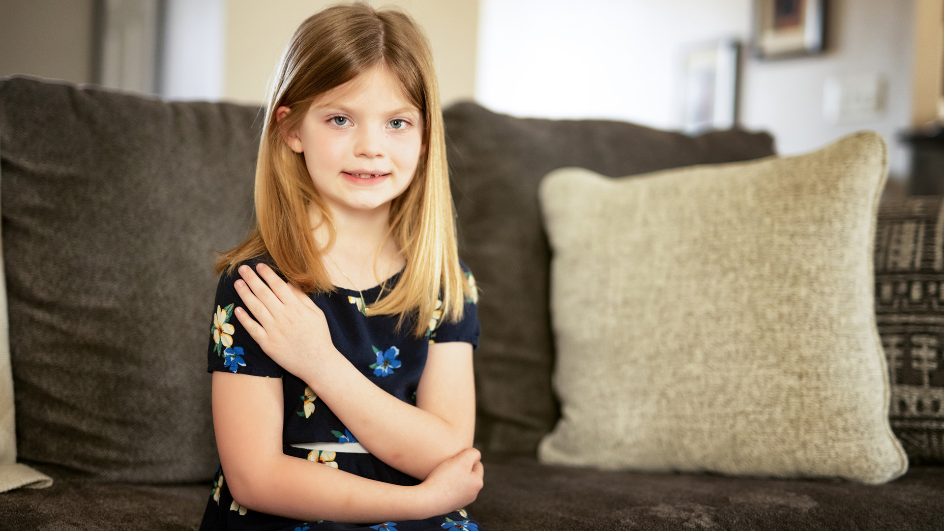 a young girl sitting on a sofa in her home