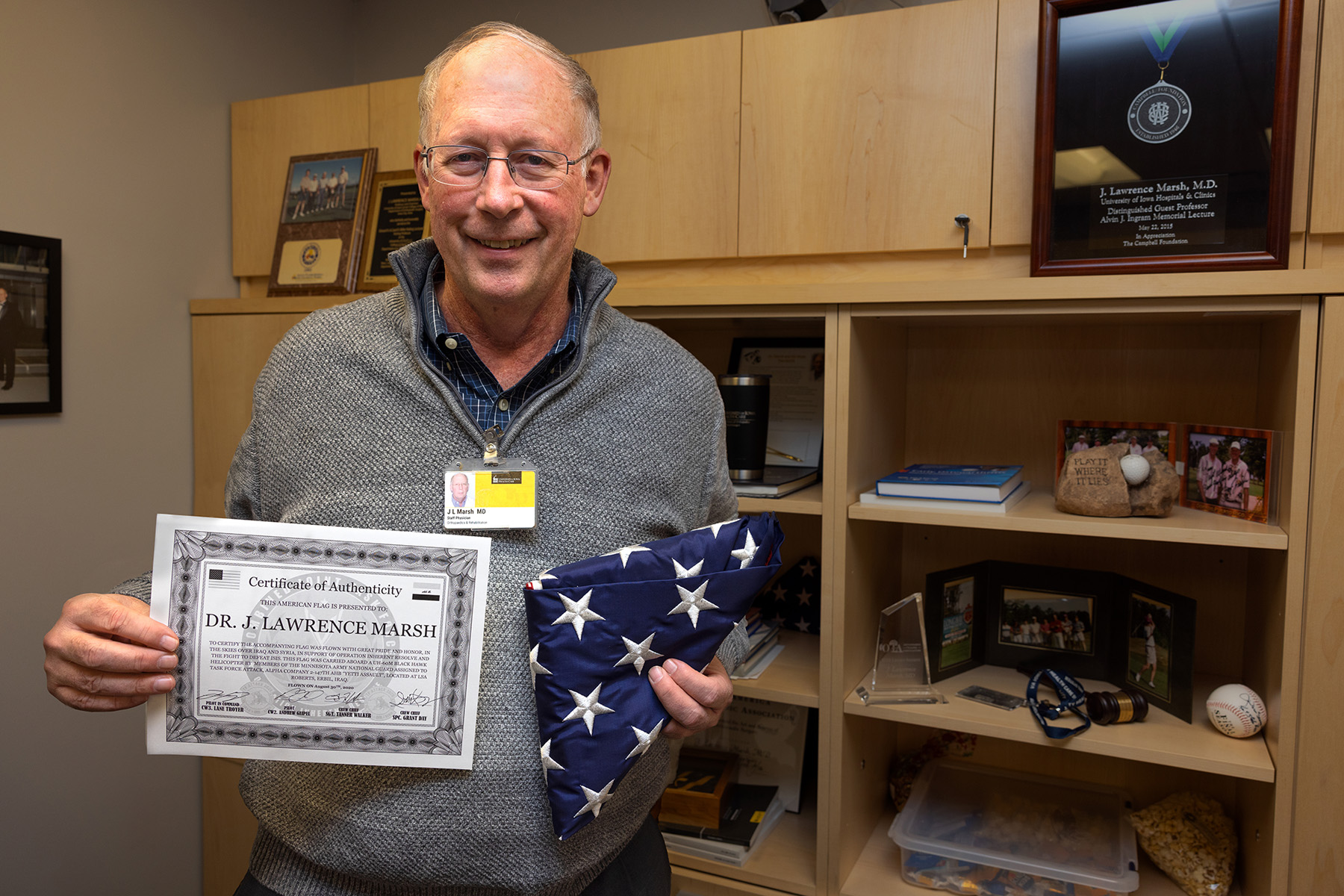 A man holding up a certificate and a folded American Flag