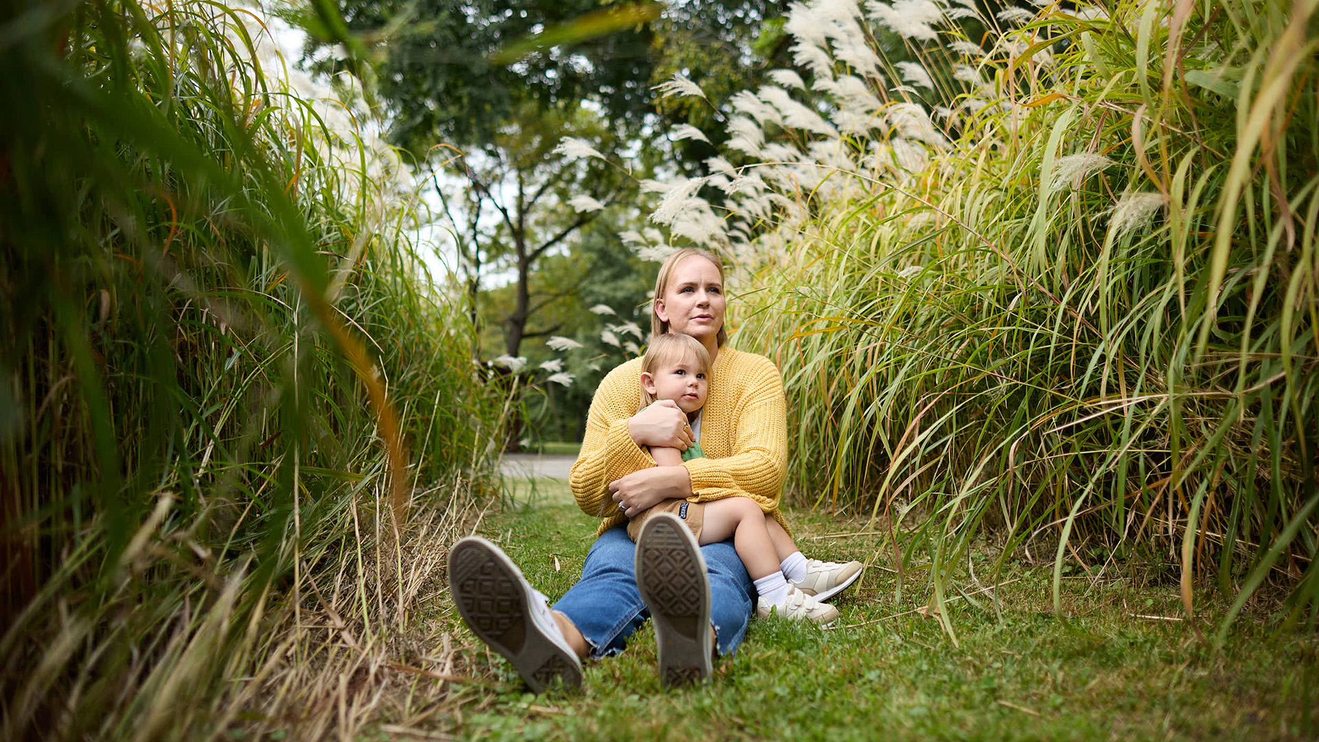 a woman holds her child while sitting in a field