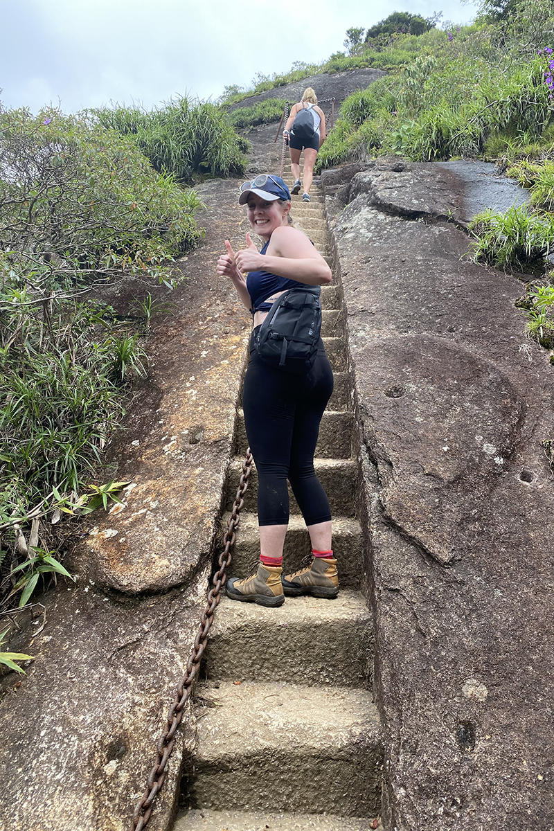 A woman giving a thumbs up while walking up steps on a mountain