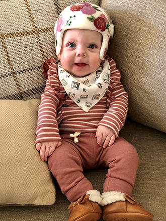 A baby wearing a flowery helmet