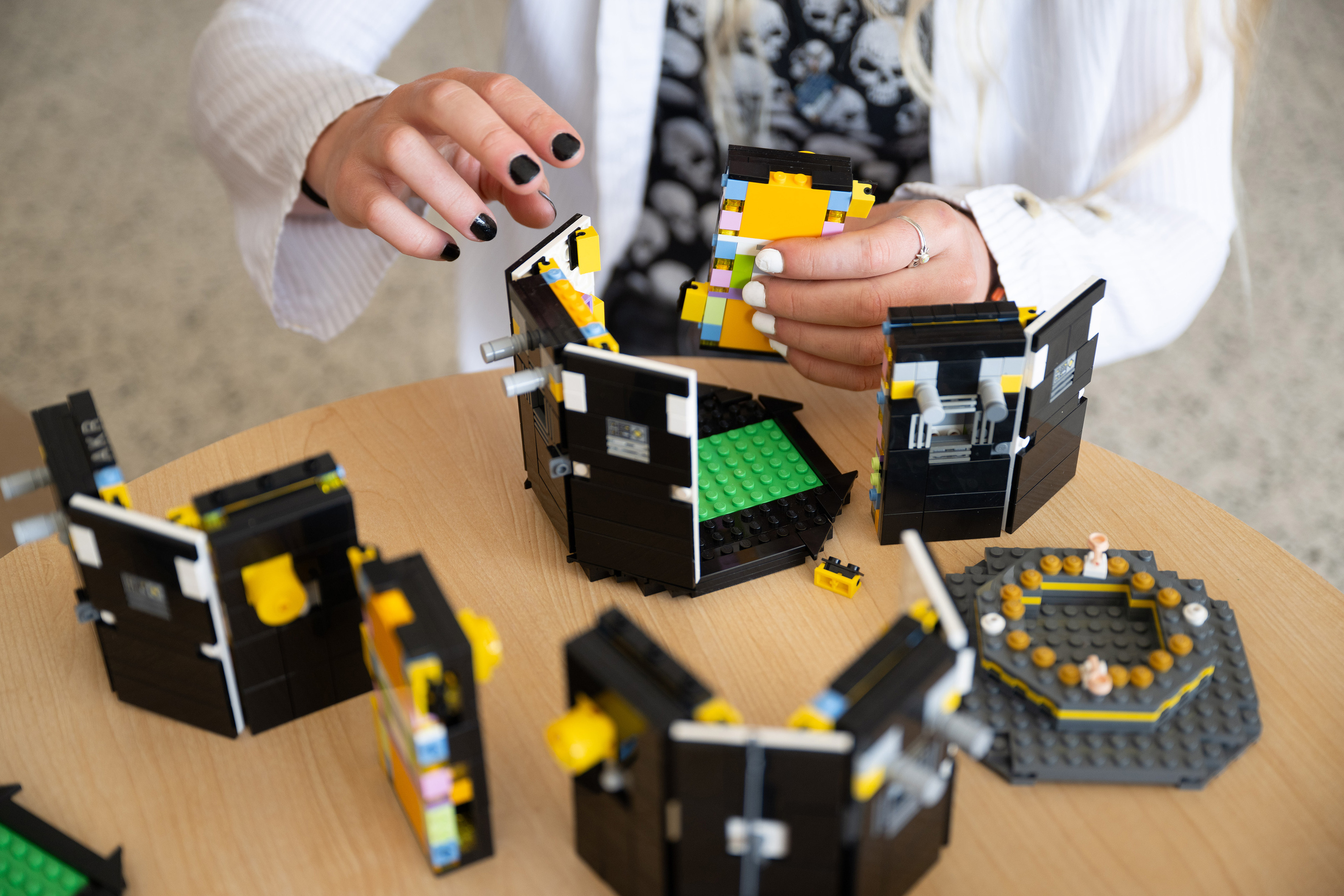 University of Iowa student Ava Reed works on a model-sized version of the spacecraft in TRACERS built with toy bricks.