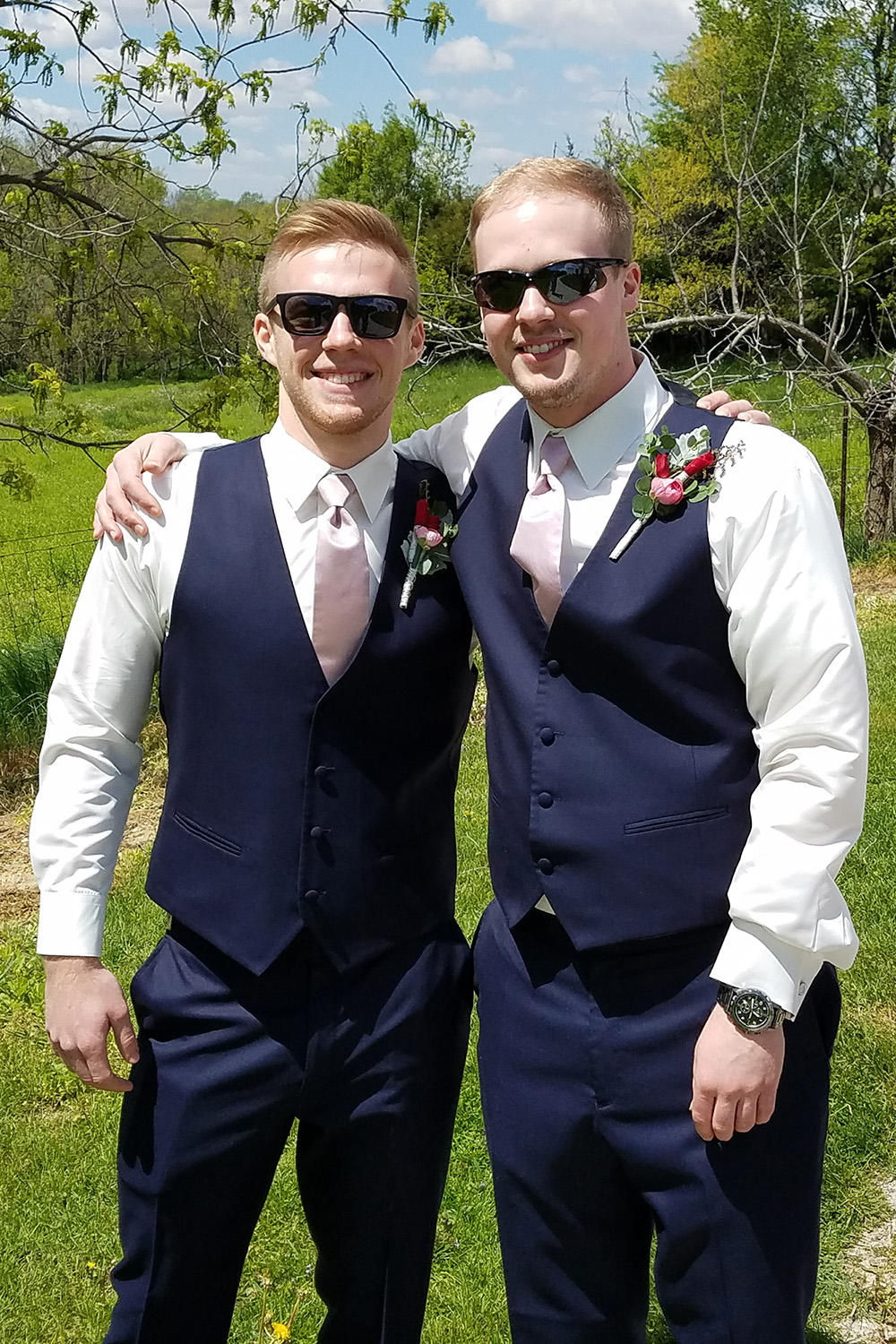 two brothers wearing suits with their arms around each other