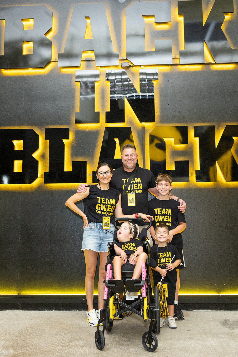a family posing in front of the "Back in Black" display at Kinnick Stadium