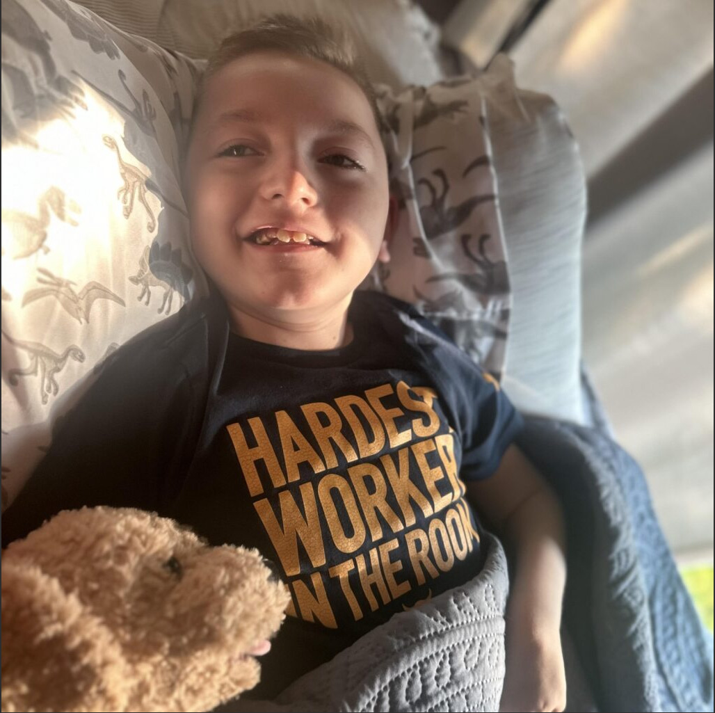 Kid Captain Liam Bartleson lying in bed with a dog