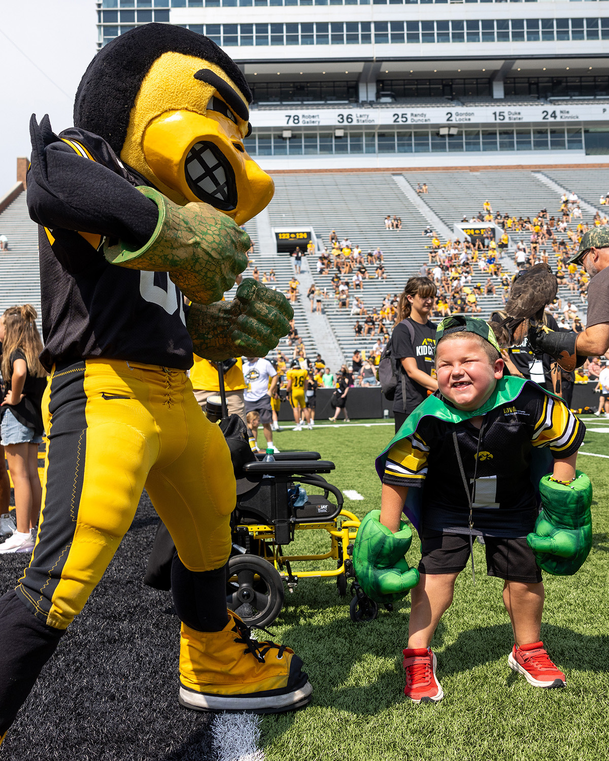 Micah Norby and Herky wearing Hulk hands at Kids Day at Kinnick