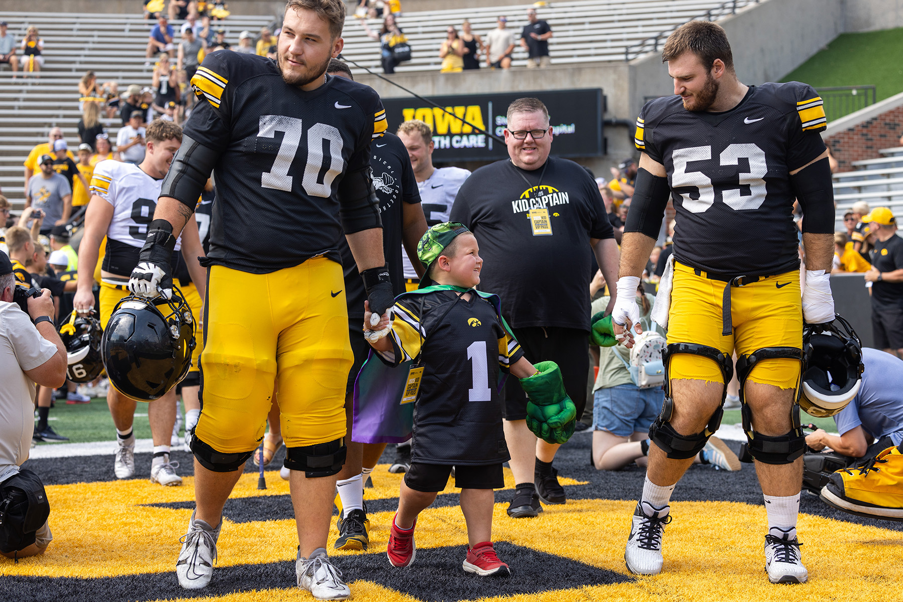 Micah Norby taking the field with members of the Iowa Hawkeyes football team