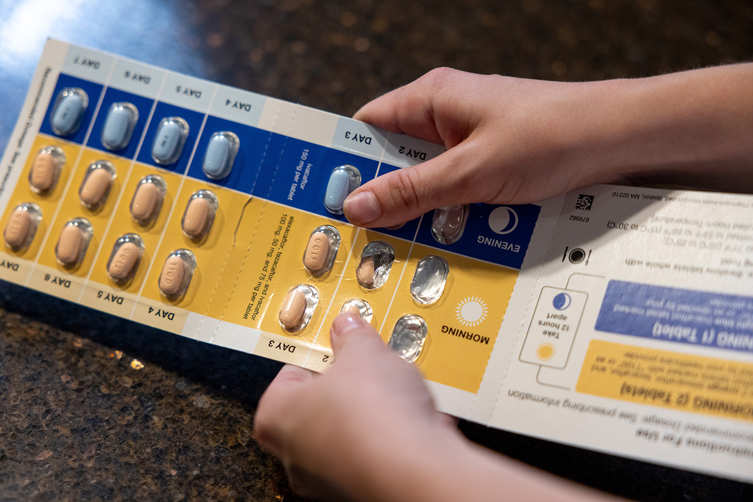 a person removing medication tablets from their container