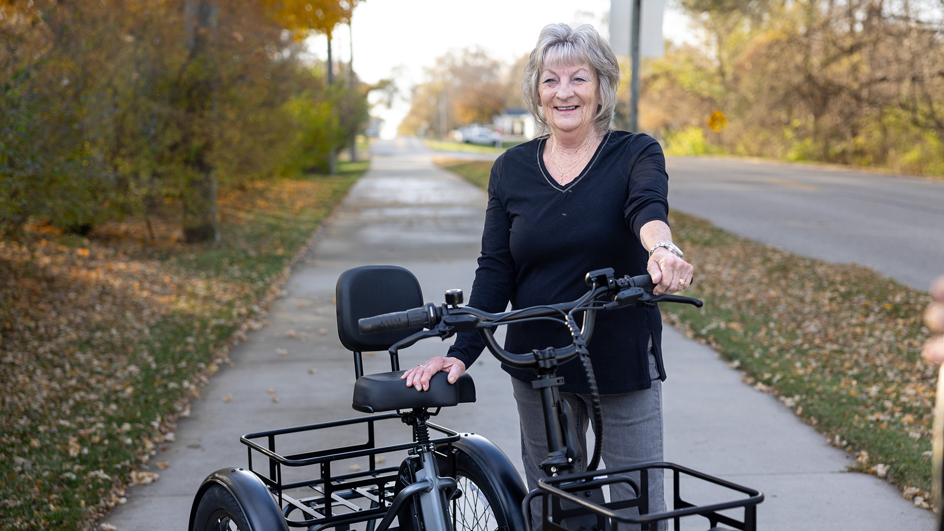 a woman standing outdoors next to a pedal-powered vehicle