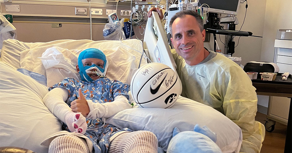 a burn patient in a hospital bed gets a visit from University of Iowa basketball coach Ben McCollum