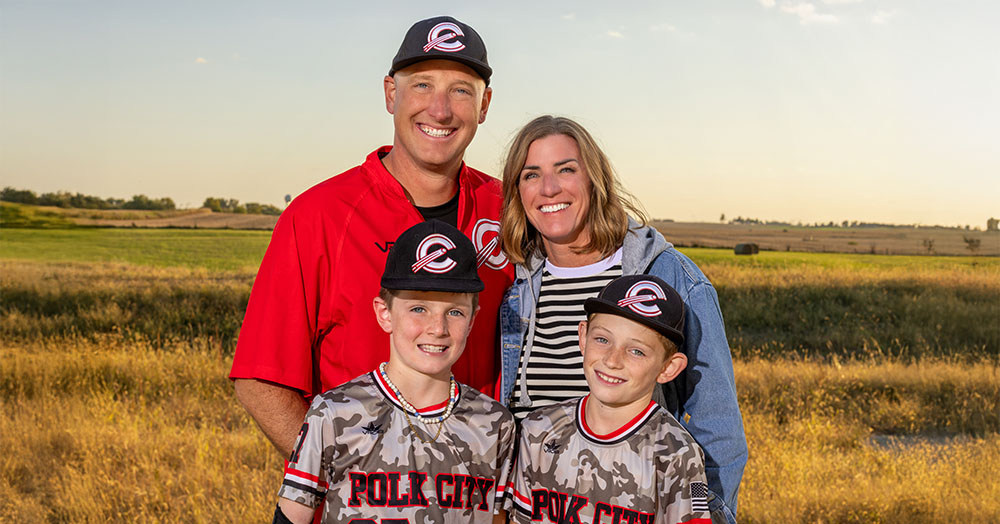 the Pearston family (mom, dad, two young boys) stand outdoors for a family portrait