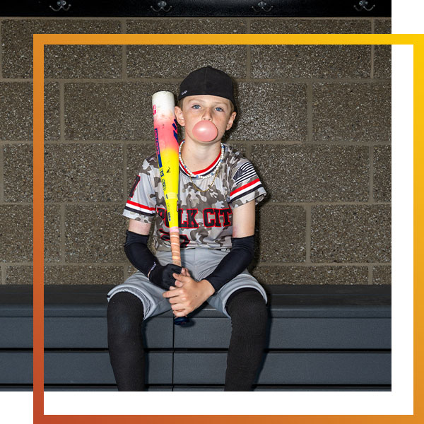 a boy holding a baseball bat in a dugout
