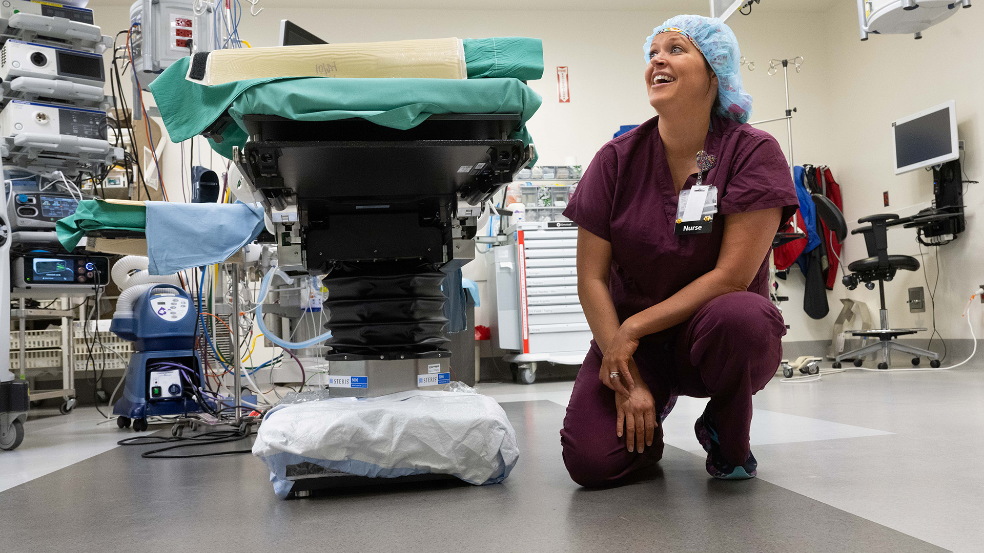 a nurse crouches down next to a hospital bed with a protective product around its base