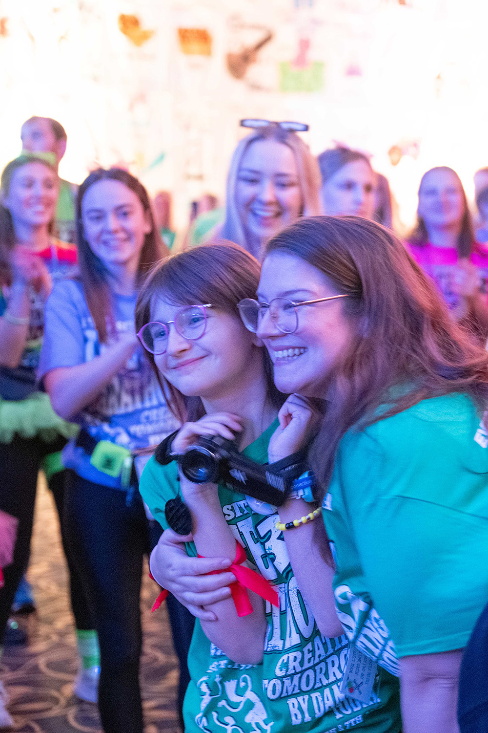 a girl and her mom embrace while dancers cheer