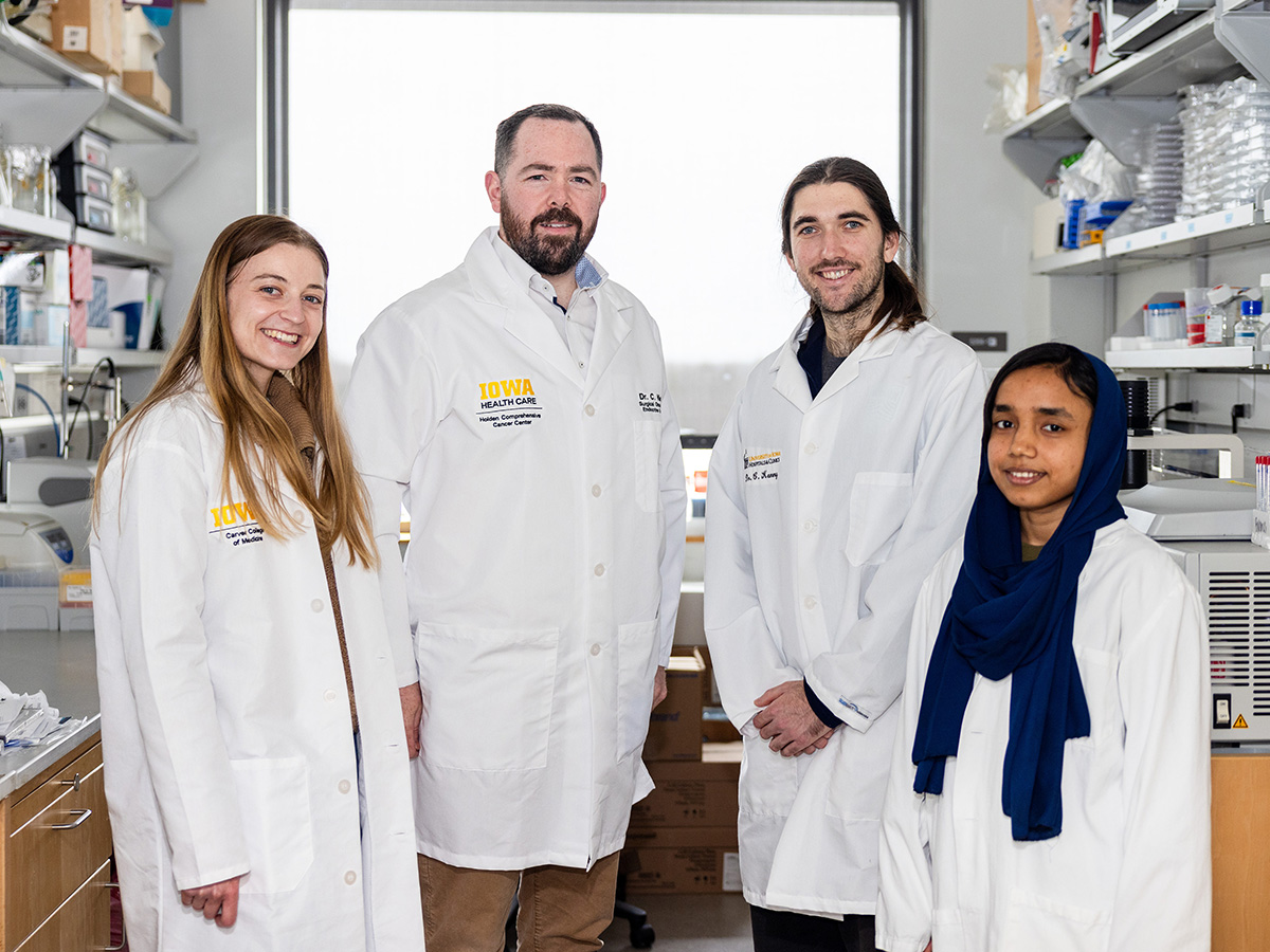 four people in white coats stand in a lab setting