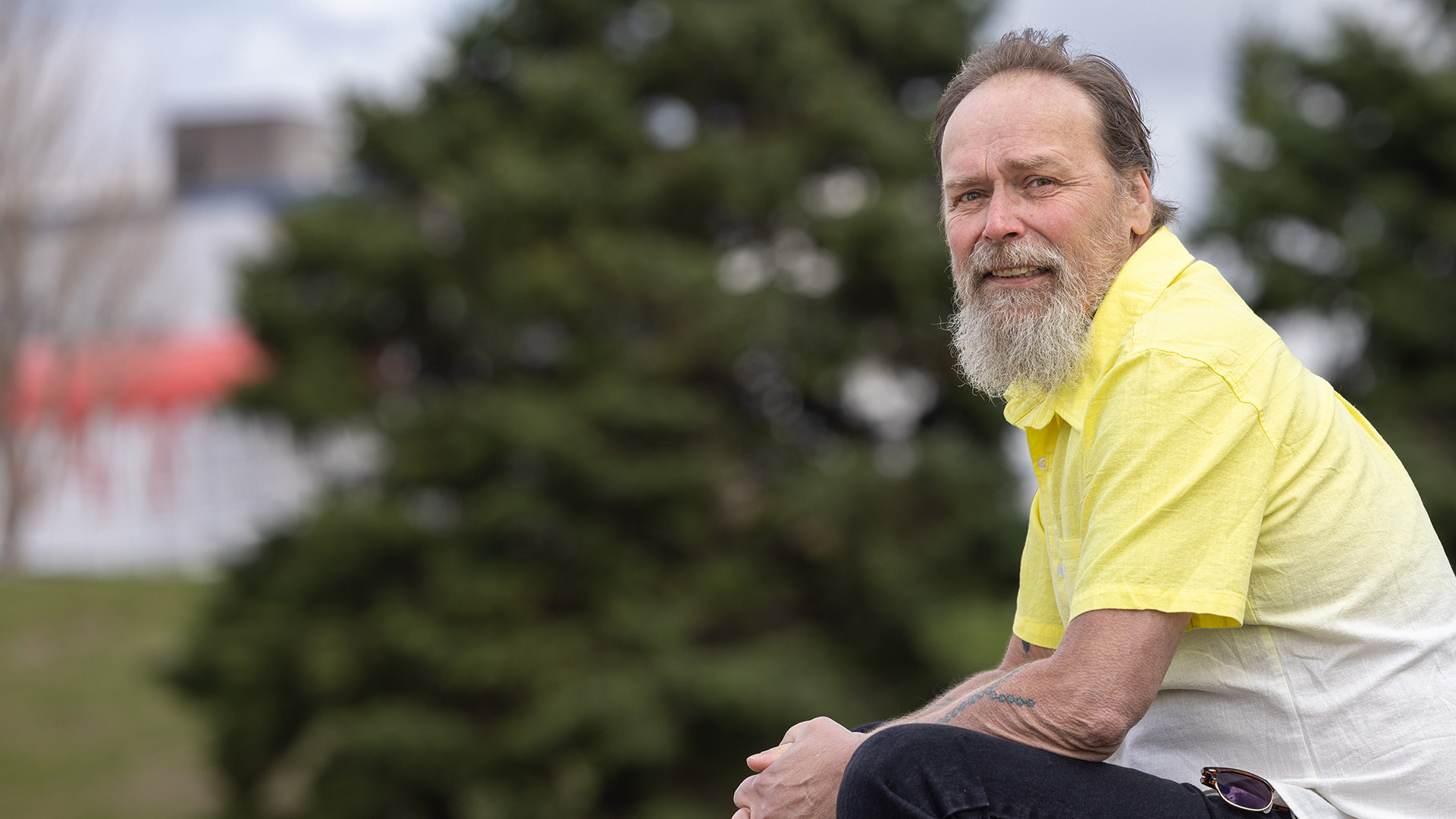 a man sitting outdoors with trees in the background