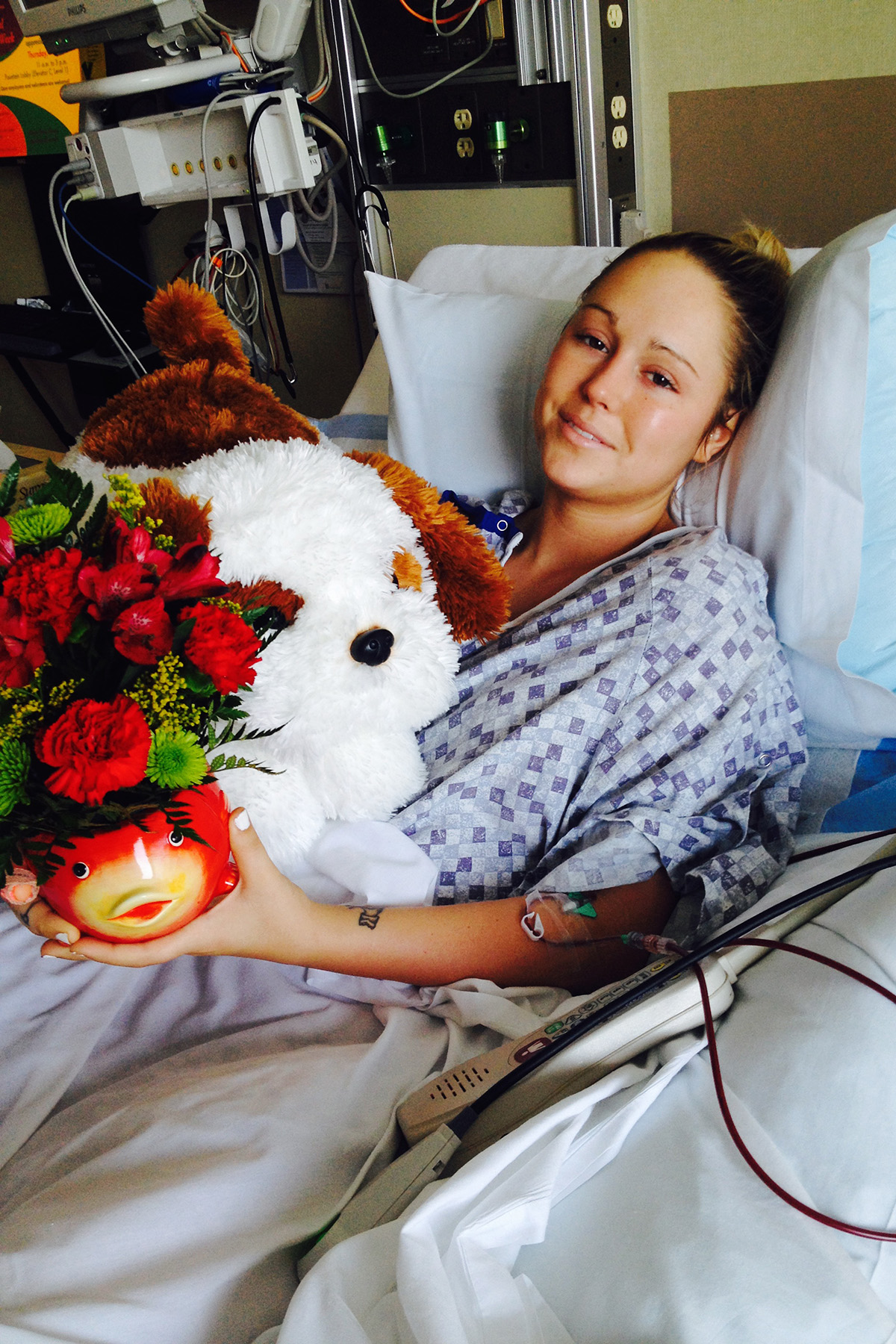 a young woman lying in a hospital bed with a stuffed animal