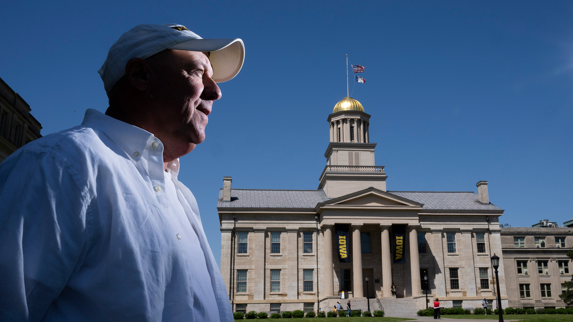 a man looks off in the distance while standing on the Pentacrest at the University of Iowa. Old Capitol is visible in the background