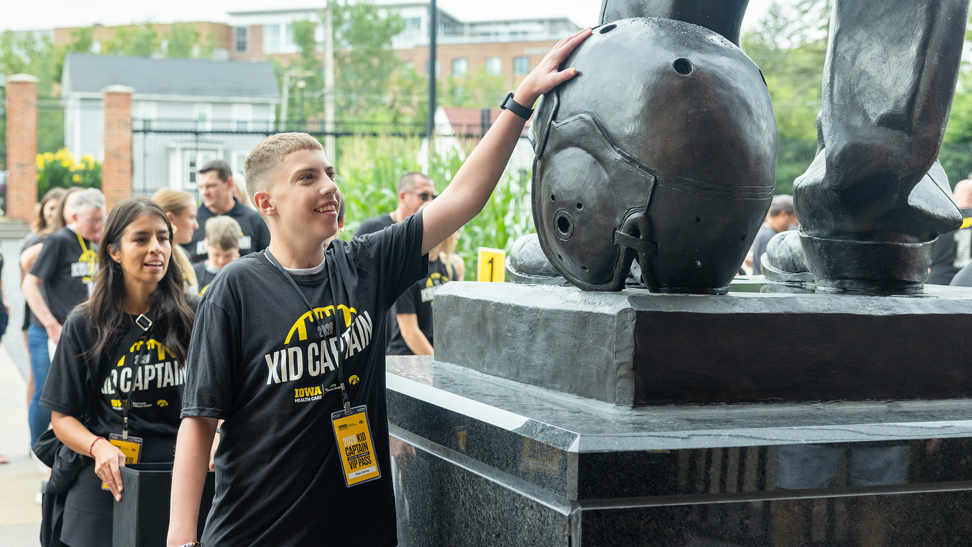 a boy touches the helmet portion of the Nile Kinnick statue outside Kinnick Stadium