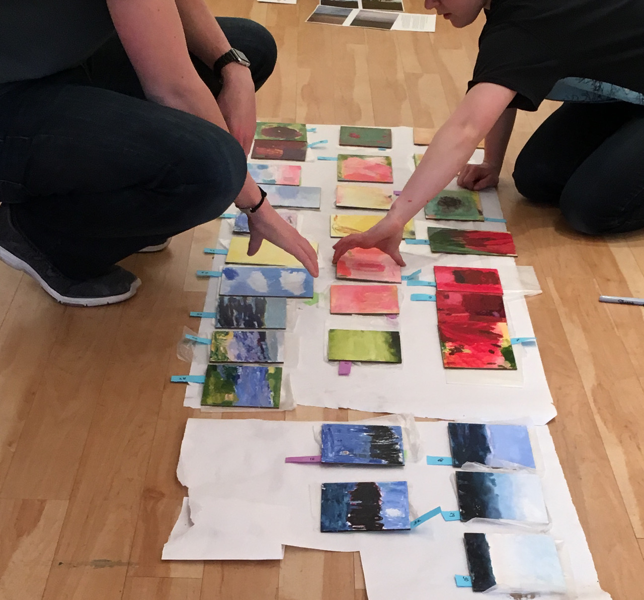 students arranging artwork on paper