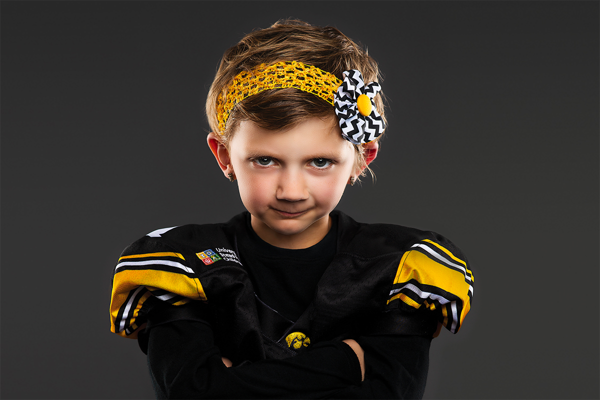 university of iowa stead family children's hospital patient and kid captain harper stribe posing in hawkeye jersey