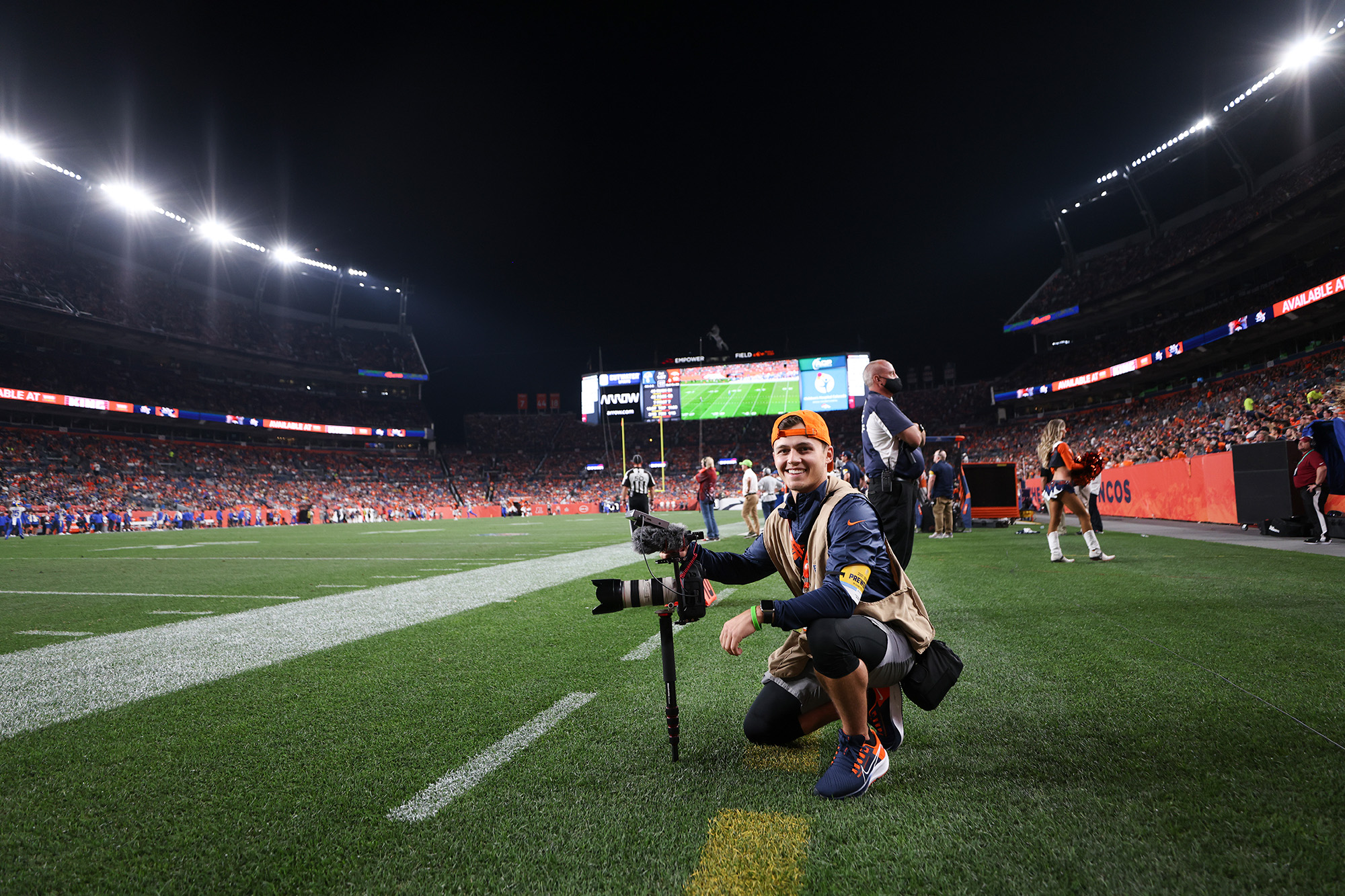 university of iowa alumnus cole cooper holding a camera on the sidelines of a denver broncos game