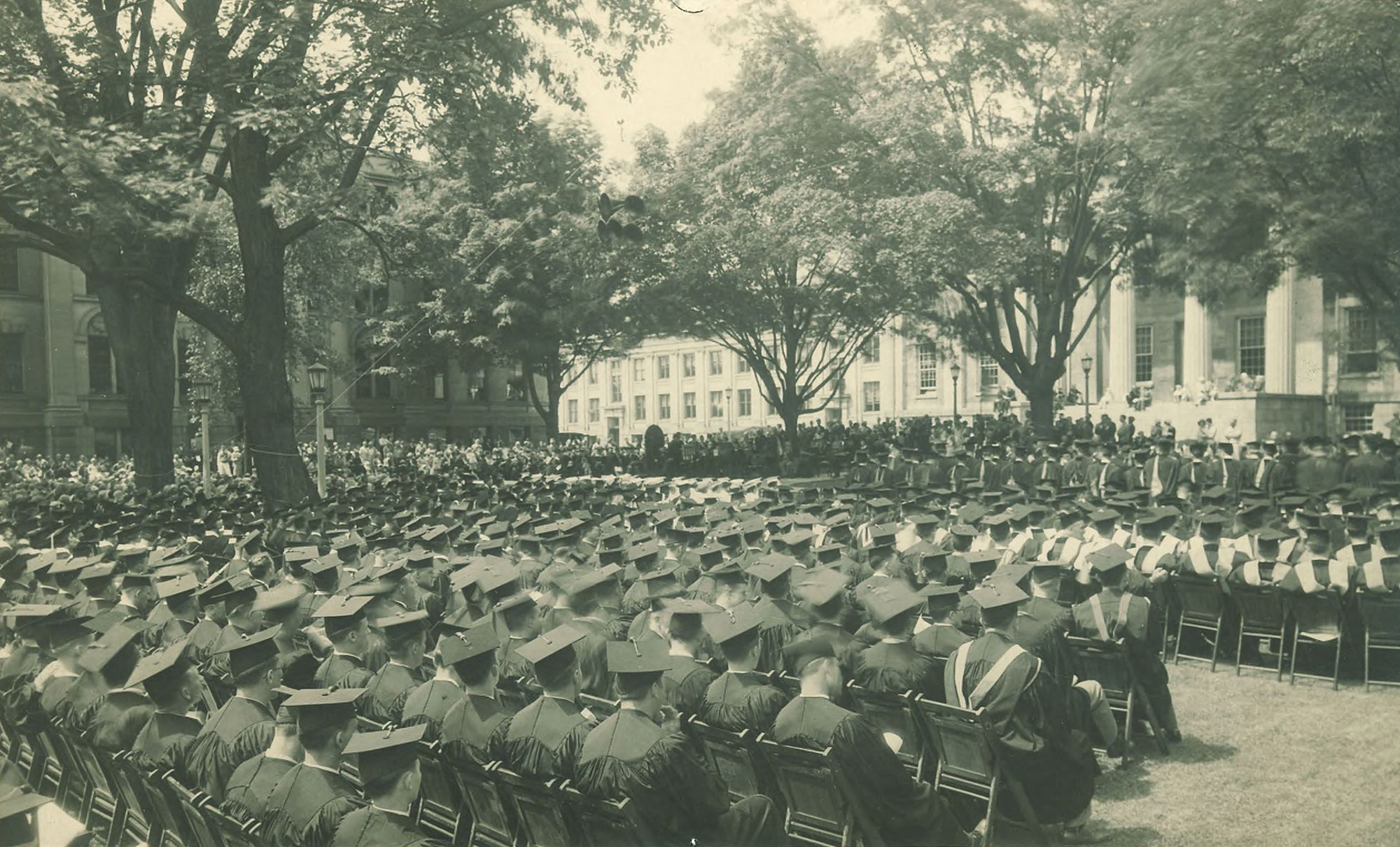 A commencement ceremony featuring hundreds of graduates outside Old Capitol at the University of Iowa in the early 20th century