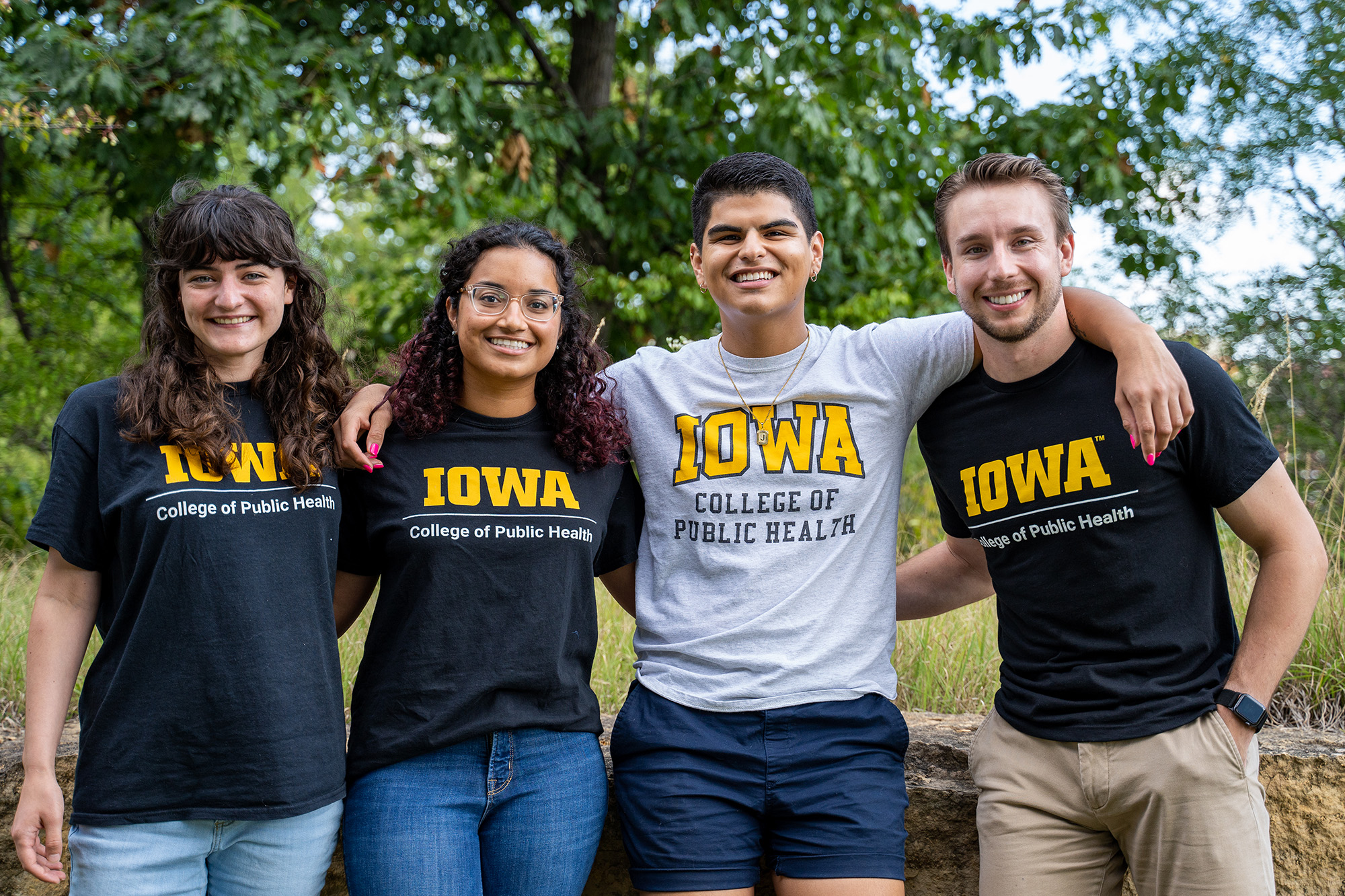 four University of Iowa student podcasters pose for a group photo in an outdoor setting