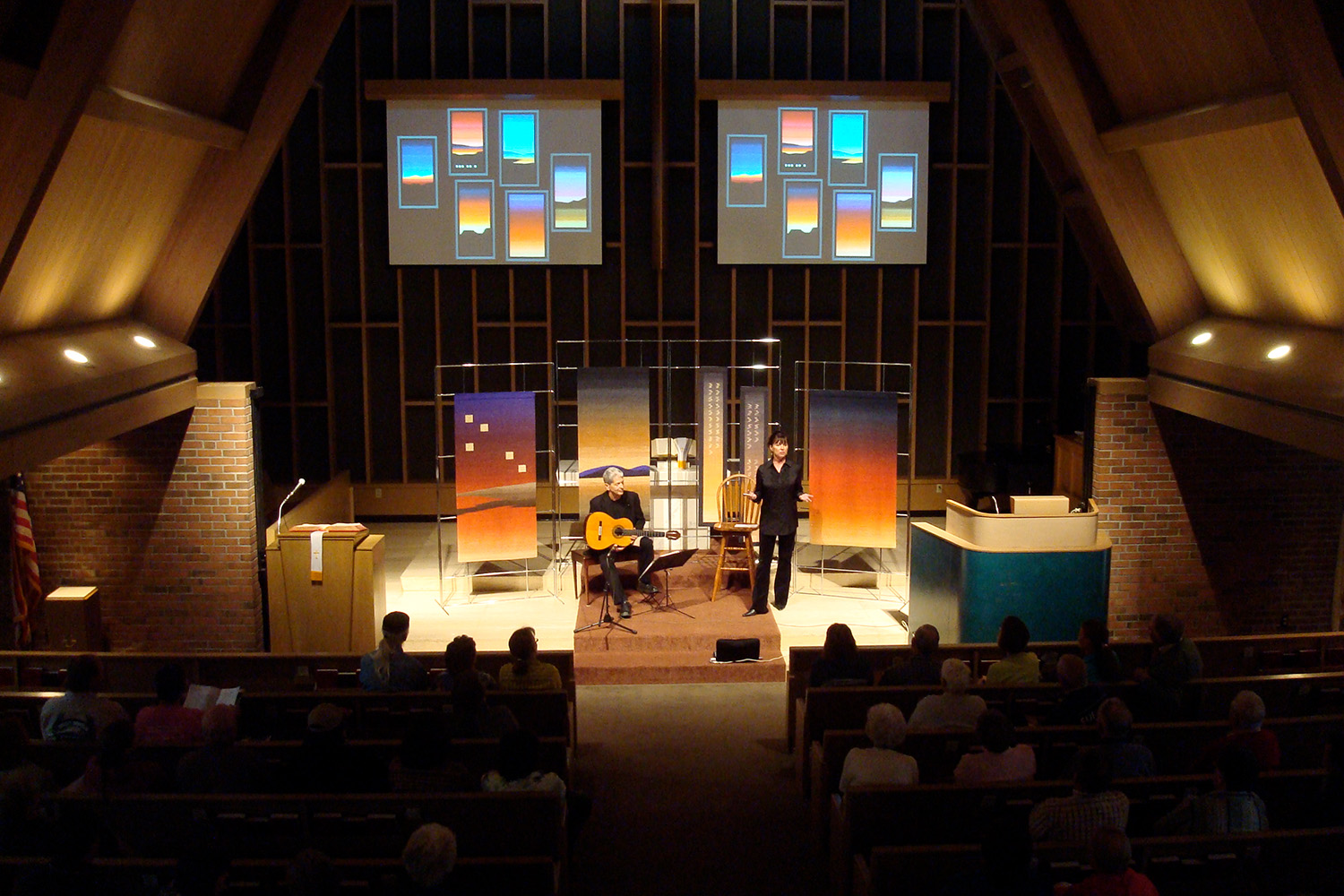 two performers, one with a guitar, on a stage