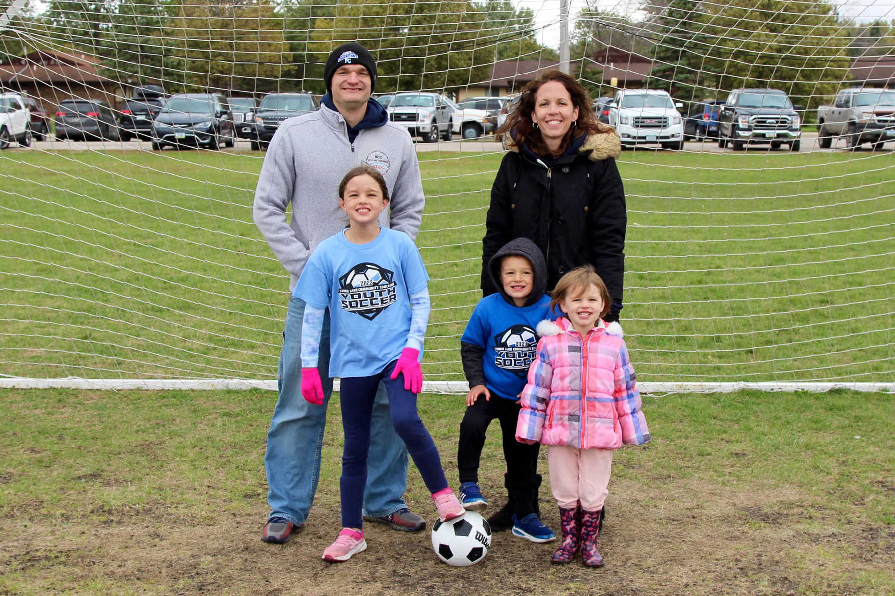 a family of five standing in front of a soccer goal