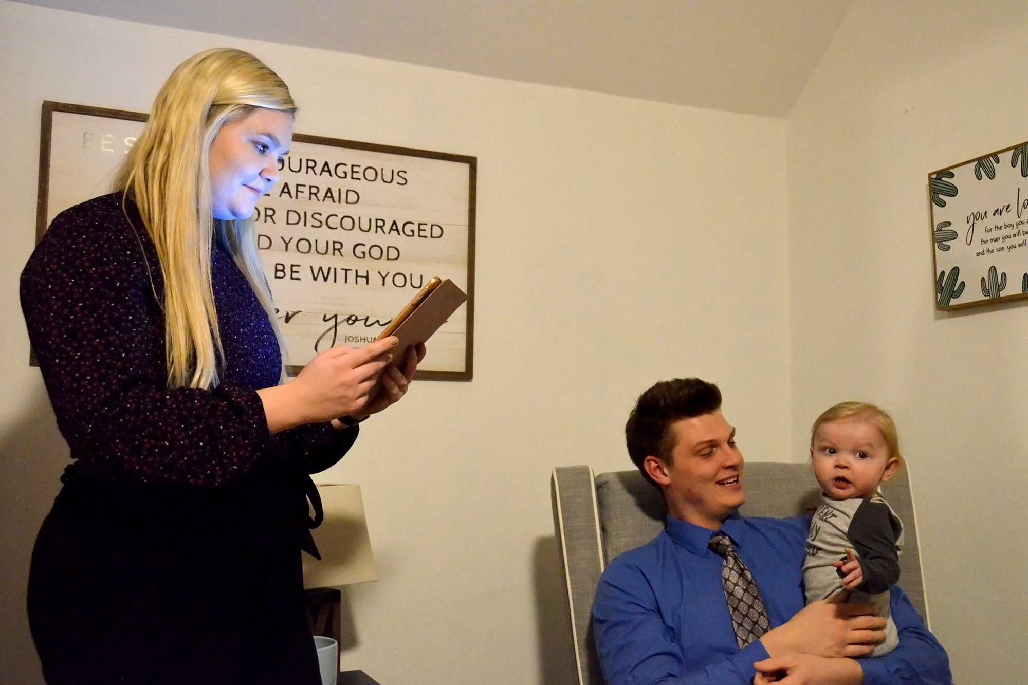 Halle Howard uses a tablet while Ethan Howard holds their son Charlie in their Springville home