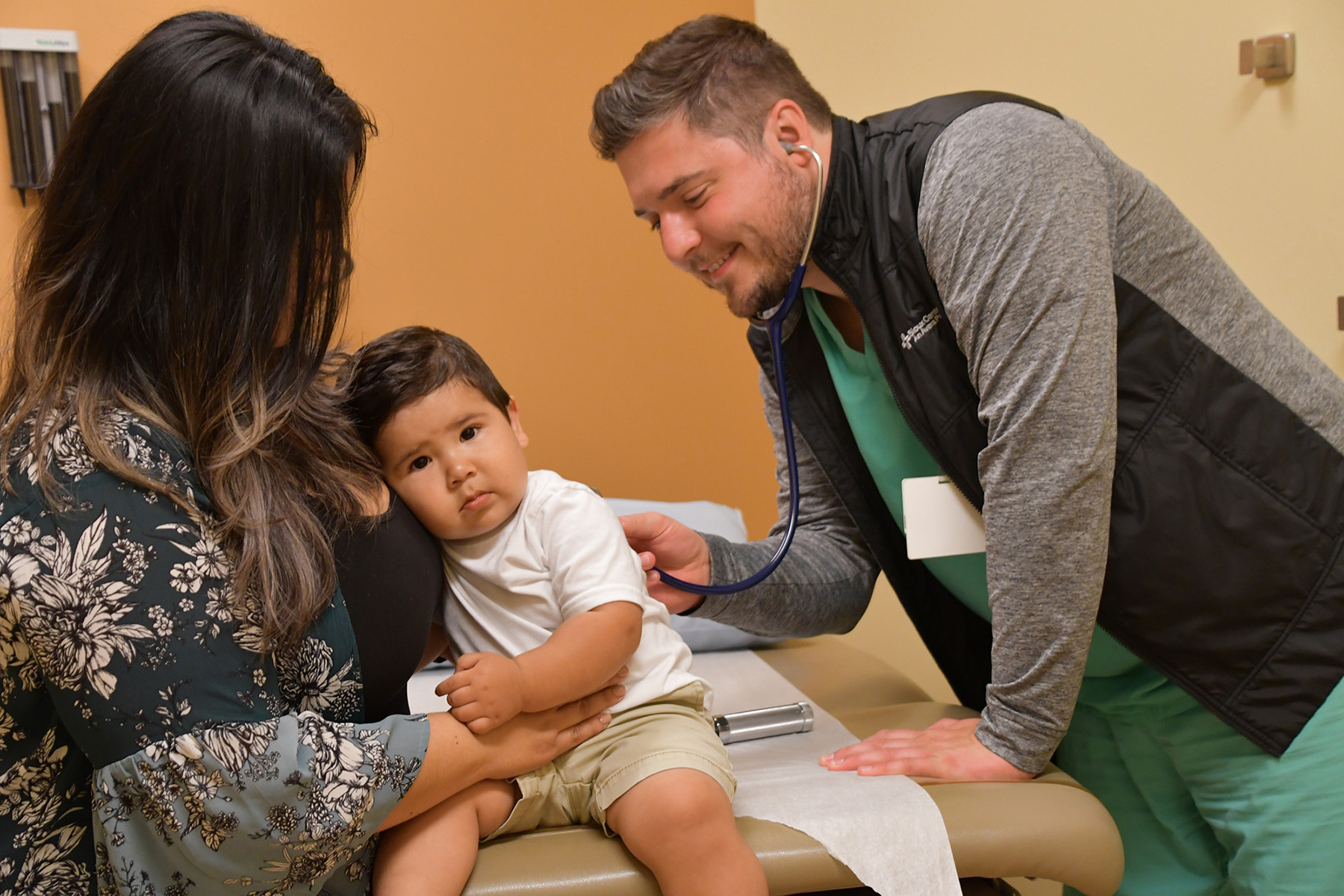 University of Iowa Carver College of Medicine graduate David Janssen sees a pediatric patient and the child's mother at his clinic
