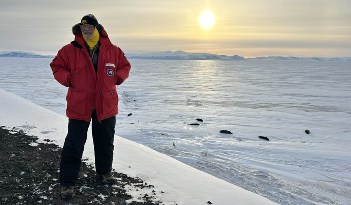 a man standing outdoors with seals on the ice in the background