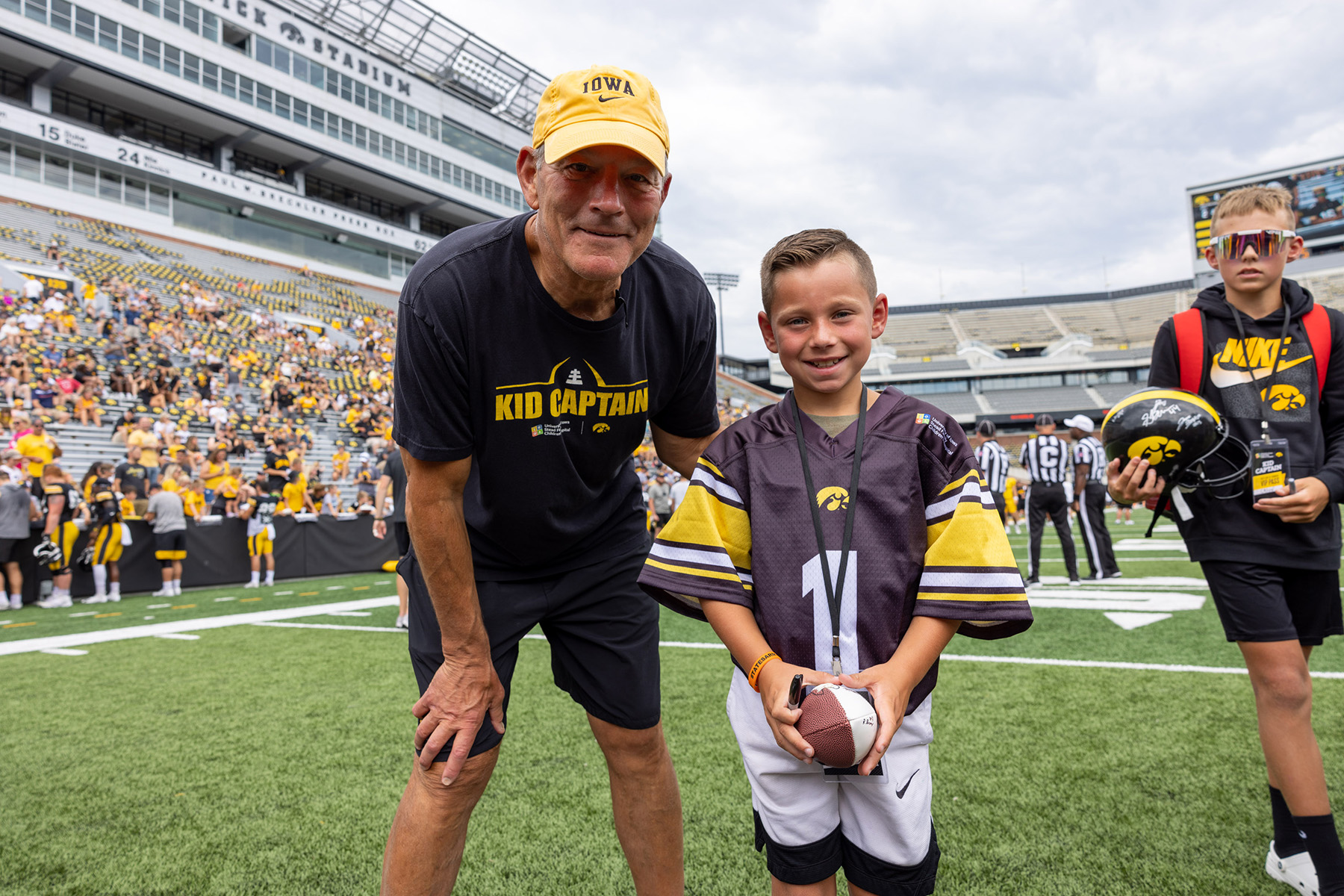 Kid Captain Tate Manahl on the field at Kinnick Stadium with Kirk Ferentz