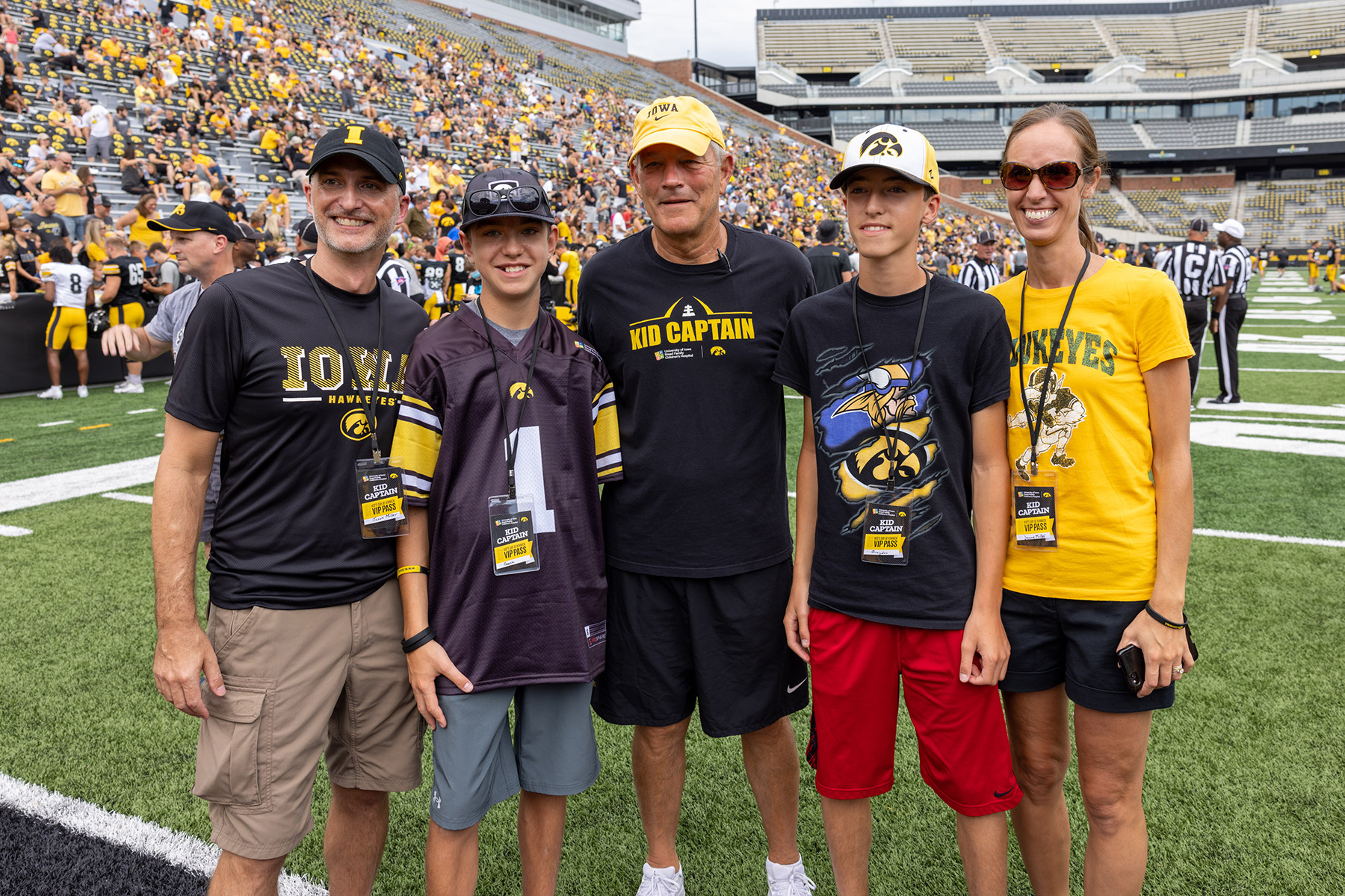 Kid Captain Gavin Miller on the field at Kinnick Stadium with family members and Coach Kirk Ferentz