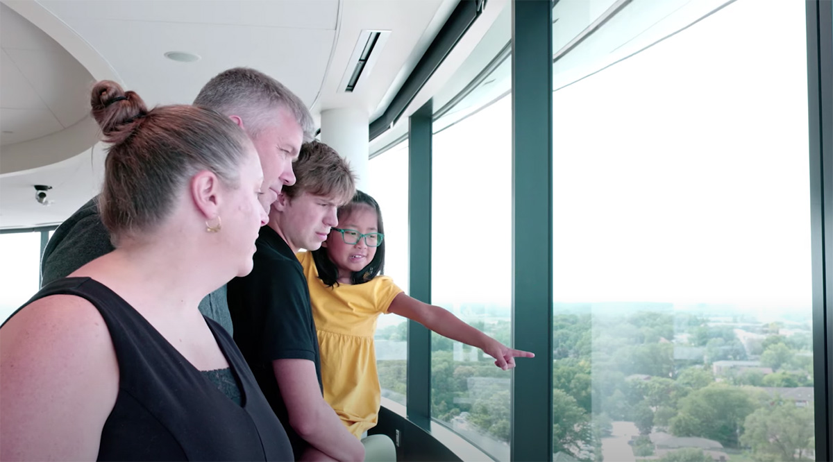CC Hoover and her family looking down at Kinnick Stadium from an observation room in University of Iowa Stead Family Children's Hospital