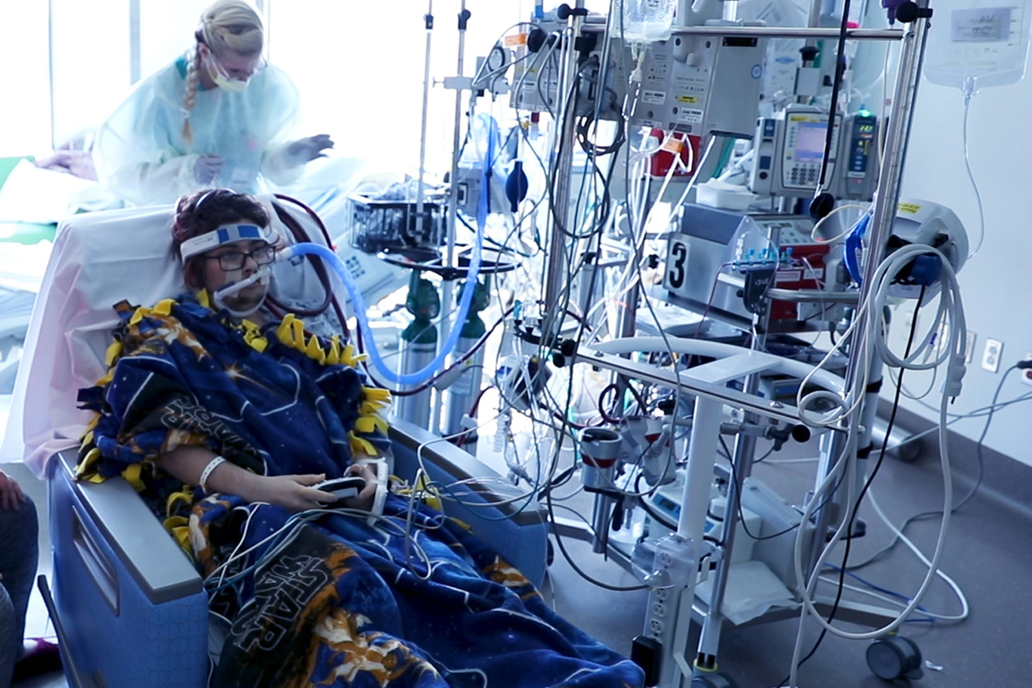 a patient on extracorporeal membrane oxygenation sits in a hospital room