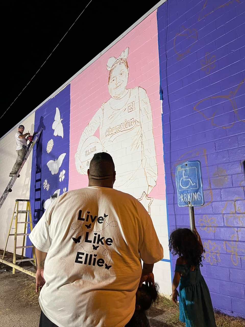Eliahna “Ellie” Garcia's father watches Abel Ortiz-Acosta paint a mural dedicated to his daughter.