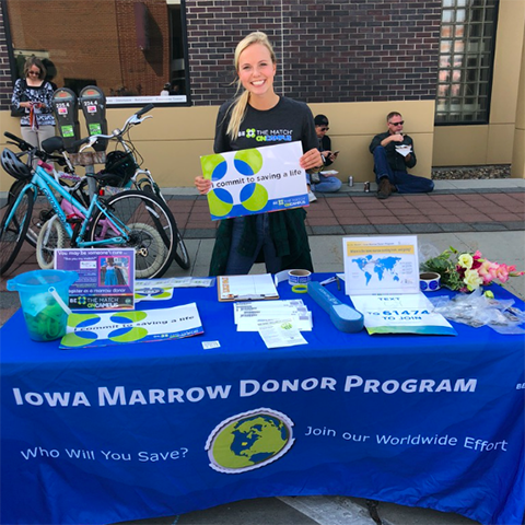 Maddie Huinker at an information table at the Ames Farmers Market in 2019