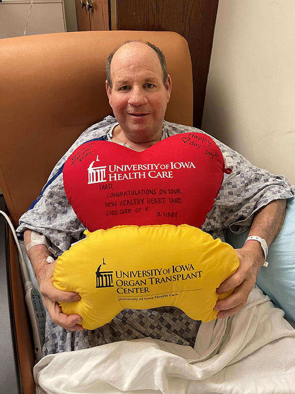 a transplant patient holds pillows that represent the two organs he received, a heart and a kidney