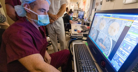 a health care professional looking at brain images on a monitor