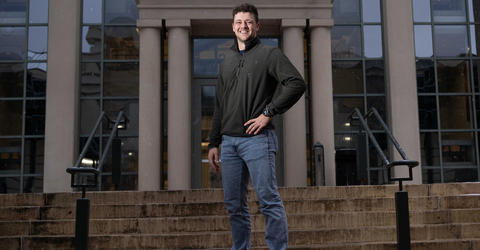 University of Iowa graduating student Noah Tarantello stands in front of a building on campus