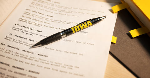 a screenplay on a desk, with an Iowa pen resting on top